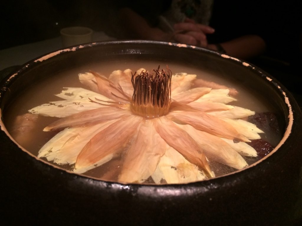 Soup with a closed up lotus flower that opens up as the steam gets into the petals